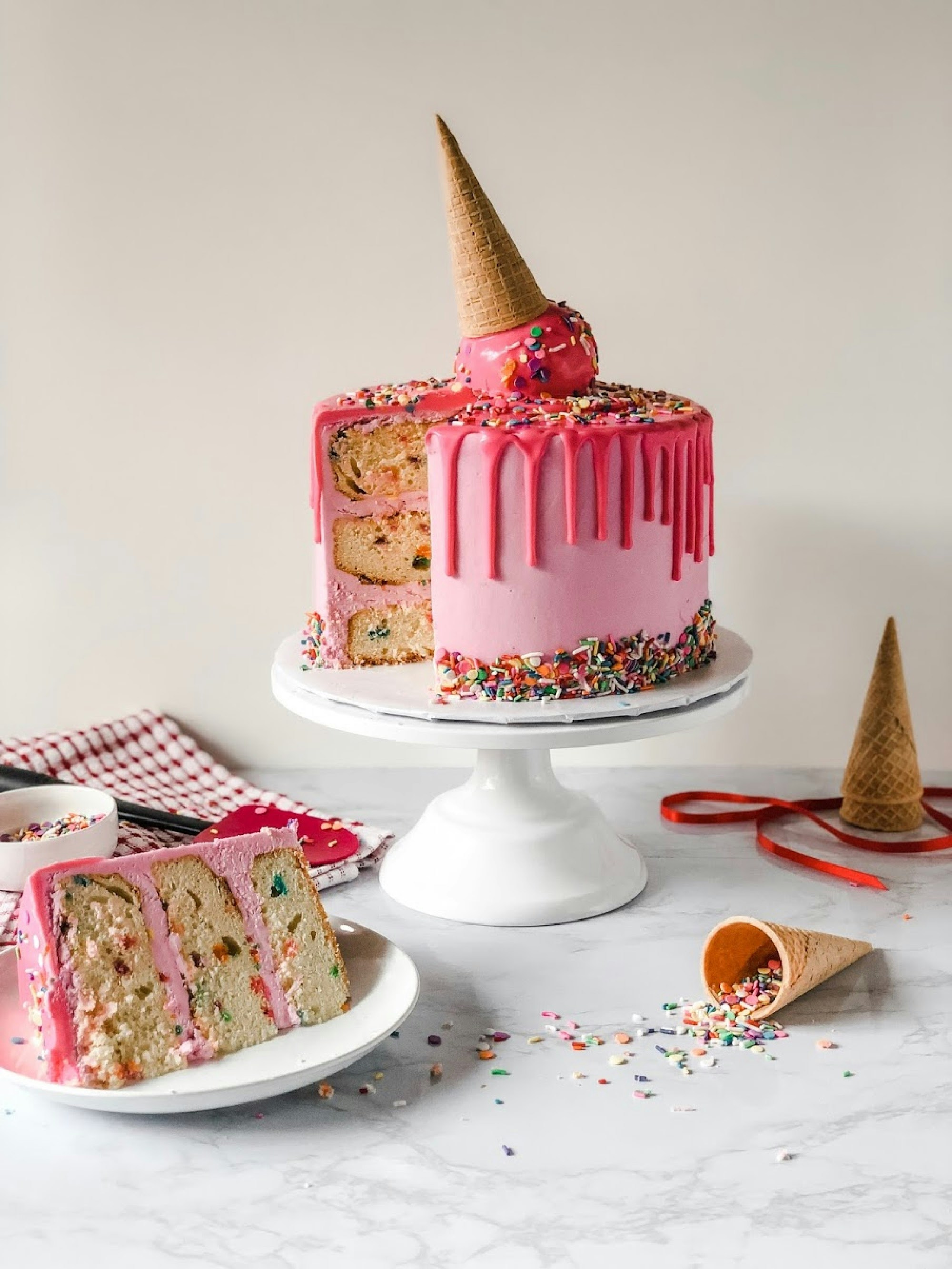 アイスクリームコーンとカラフルなスプリンクルを飾った、ピンクのホールケーキ